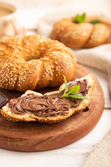 Homemade sweet bun with chocolate cream and cup of coffee on a white wooden. side view, selective focus.