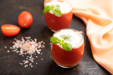 Tomato juice with basil and himalayan salt in glass on a black background. Side view, selective focus.
