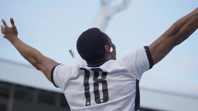 Portrait of African Black male soccer football player celebrating victory in the championship, lifting the trophy above his head in a huge stadium. Super slow motion shot