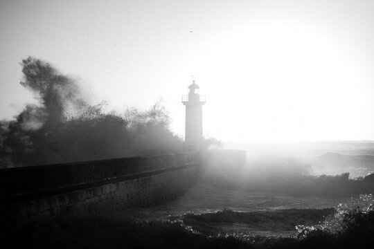 Huge wave at Lighthouse, Portugal. Black and white photo with grainy film effect.