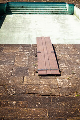 Old Fashioned Wooden Diving Board Over A Drained Swimming Pool