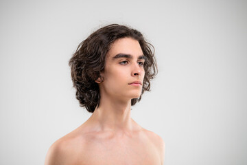 Portrait of a handsome young man with lush curly hair on a white background