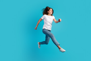 Fototapeta na wymiar Photo of pretty charming woman dressed white outfit jumping high running fast empty space isolated blue color background