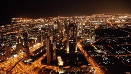 Panorama de la ville de Dubai de nuit pris depuis le sommet du Burj Khalifa, plus haut immeuble du monde. On y voit les autoroute, les routes, les échangeurs,  les lumières, les autres buildings.