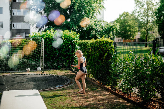 Children Running Through Garden Sprinkler