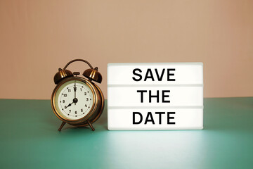 Save the Date text message on paper card with wooden easel and alarm clock