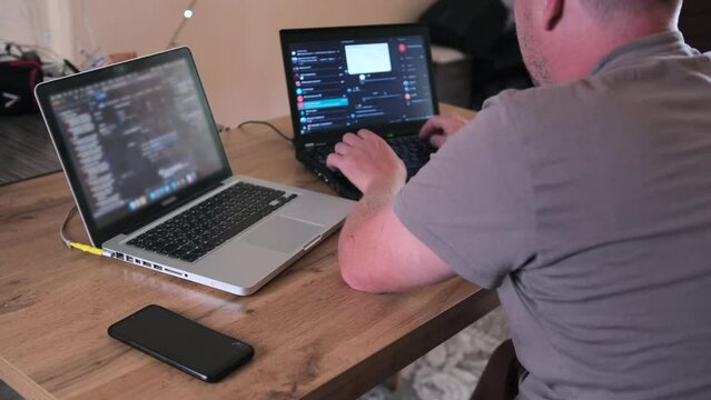 Side back view developer software  IT specialist programmer man work at home, writing code on laptop. Program development concept.