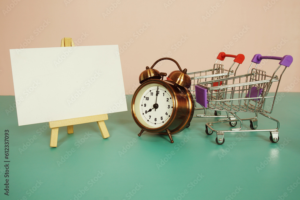 Poster card mockup space for copy text message on easel standing with alarm clock on pink and blue backgrou