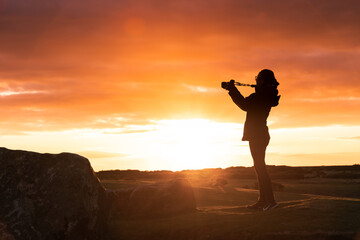 Silhouette of a woman photographing the sunset