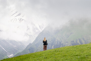 A young woman admires the majestic view of the panorama mountain landscape.