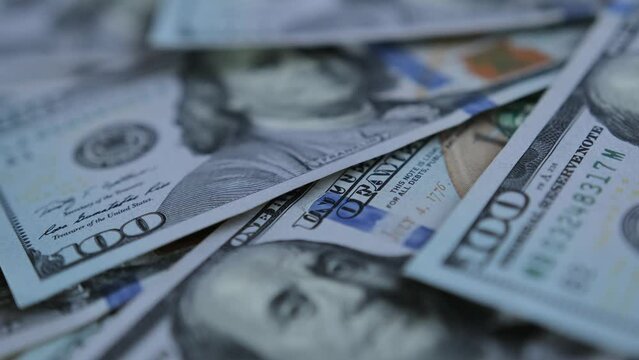 Slow motion close-up hundred dollar banknotes on table. Many 100 dollar bills cash. Financial management and budgeting.