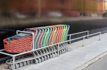  A row of empty colorful shopping carts near the supermarket. Consumer concept.