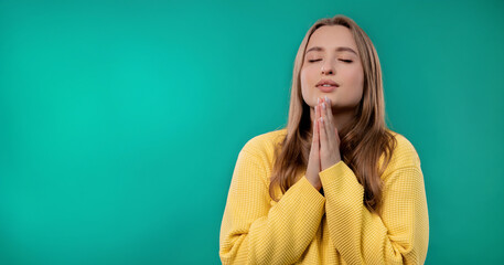 Young woman praying, begs to apologize her, she is guilty. Blue background.