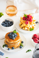 Summer breakfast. Homemade baked ricotta pancakes and Belgian waffles with fresh berries on white wooden table