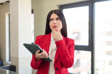 pretty young woman smiling with a happy, confident expression with hand on chin. touch screen pad concept