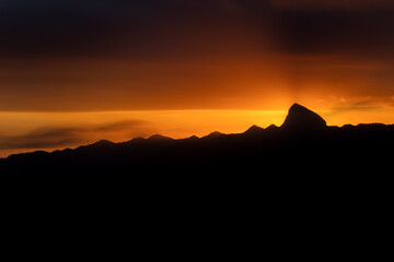Majestic Mountain Peak Silhouette at Sunset with Vibrant Orange Sky