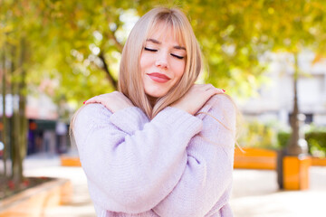 young pretty woman feeling in love, smiling, cuddling and hugging self, staying single, being...