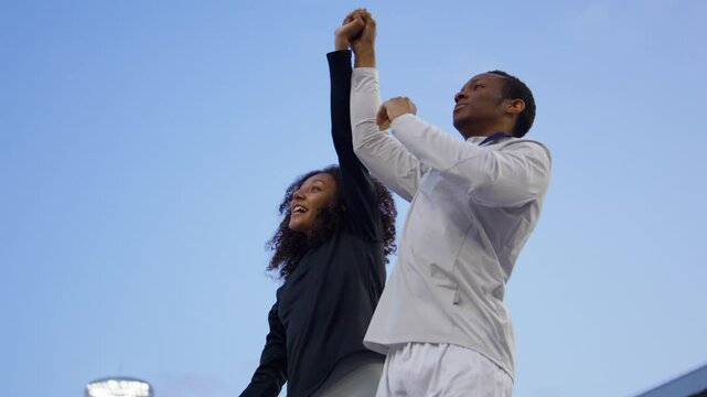 Black Male and Female Athletes Celebrate a Win on a podium after receiving gold medal. Shot on RED cinema camera