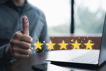 Satisfied customer concept. Hand holding up a thumb with a smiley face and five-star rating symbol...
