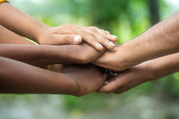 Many hands are placed together on top of each other and the background blur