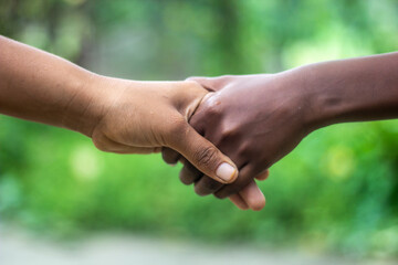 Two friends are hand-shaking, one with white hands and the other with black hands.