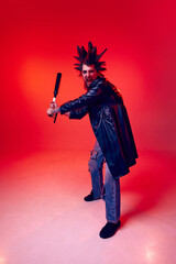Expressive young man, punk with weird hairstyle and makeup, aggressively posing with baseball bat...