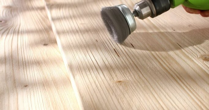 Wood brushing with wire cup brush for drill. Processing, aging and texturing of wood surface. Close up. Angle view.
