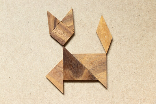 Wooden tangram in cat walking shape on wood background
