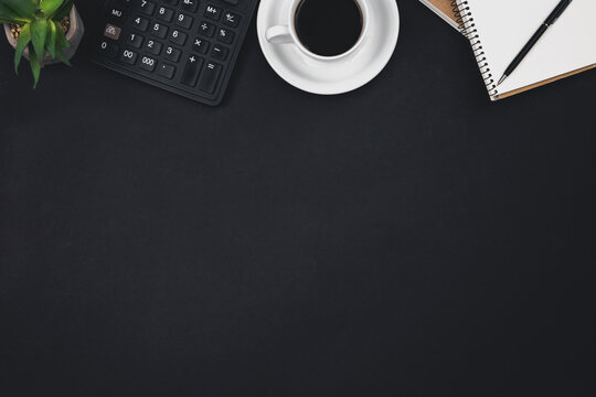 A cup of coffee, notepads, a calculator on a black background, top view.