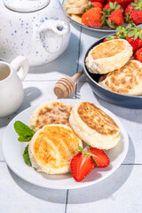 Cottage cheese pancakes, syrniki with fresh berries, sweet summer breakfast. Pan fried roasted portioned cheesecakes 