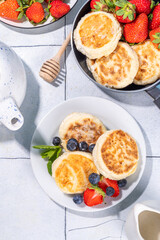 Cottage cheese pancakes, syrniki with fresh berries, sweet summer breakfast. Pan fried roasted portioned cheesecakes 