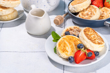 Cottage cheese pancakes, syrniki with fresh berries, sweet summer breakfast. Pan fried roasted portioned cheesecakes 