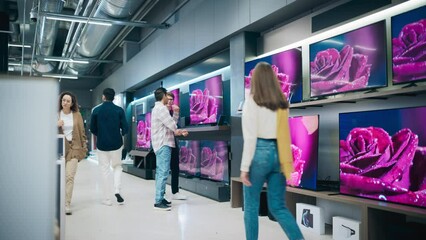 Multicultural Customer Discussing TV Choices with Electronics Store Sales Rep. Trendy Man Looking to Buy a Flat-Screen TV. Shopper Exploring Wide Variety of Television Models in Modern Retail Outlet - Powered by Adobe
