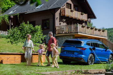 Happy family preparing for holiday, charging their electric car.