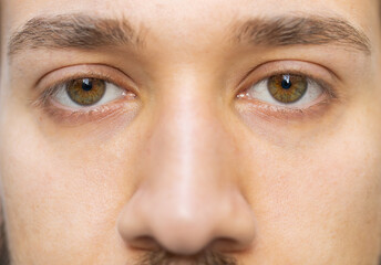 Extreme close-up macro portrait of face. Young adult handsome bearded man's eyes looking at camera. Gray green eyes of guy male boy. Middle eastern man opening blinking eyes, smiling. Laser correction