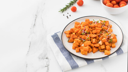 Baked sweet potato slices in a plate on the table. Healthy eating. Vegan dish. Copy space