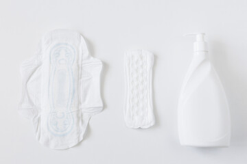 Feminine sanitary pads and liquid intimate soap on a white