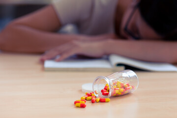Young teen student with medicine drug capsule pill for pain relief or reduce stress from studying...
