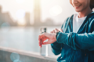 Asian woman check the pulse via a smartwatch after jogging a morning workout in the city.
