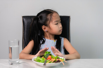 Little asian cute girl refuses to eat healthy vegetables.Nutrition & healthy eating habits for kids...
