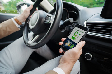 Close up of businessman using electric vehicle charging app, checking electricity usage and the nearest charging station.