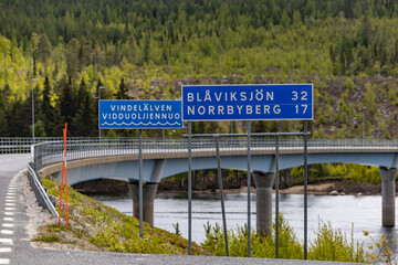 Blaviksjon, Sweden A bridge over the Vindelalven river and road signs with distances.