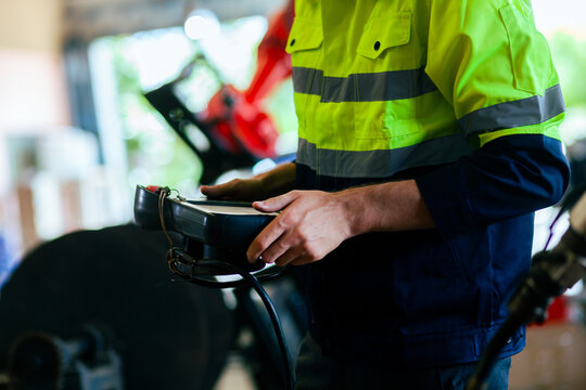 Close-up of a beautiful engineer's hand controlling an automated robotic arm in a smart factory. Welding robots in industrial plants. smart factory technology machinery in the factory. - Powered by Adobe