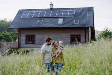 Happy family with baby near their house with solar panels. Alternative energy, saving resources and...