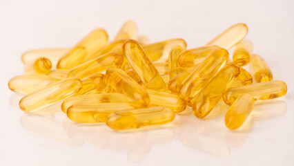 Close up of oil softgel capsules on white background with reflection. Nutritional supplement...