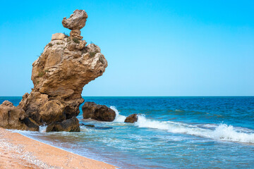 Seascape. Blue sea with a fancy stone on the shore. Travel and tourism