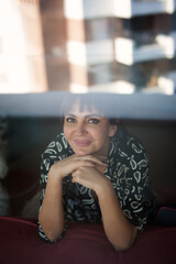 Contemporary modern woman, brunette, in a dress, standing in front of the mirror in her comfortable apartment
