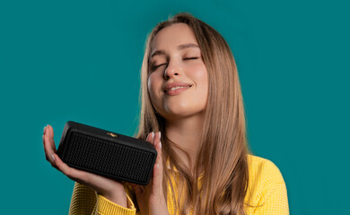 Young woman listening to music by wireless portable speaker modern sound system