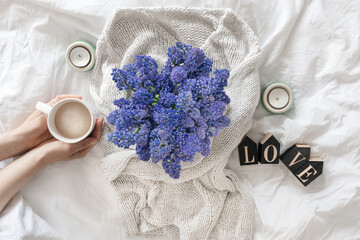A bouquet of flowers, a cup of coffee and a decorative word Love in a white bed.