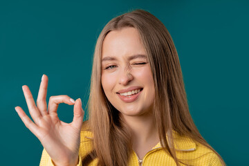 Pretty woman with OKAY sign, ok gesture. Happy lady, correct choice on blue wall